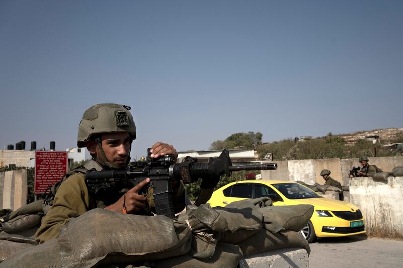 Israeli soldiers search a Palestinian taxi at a checkpoint near the West Bank town of Nablus. October 16, 2022.  AP Photo