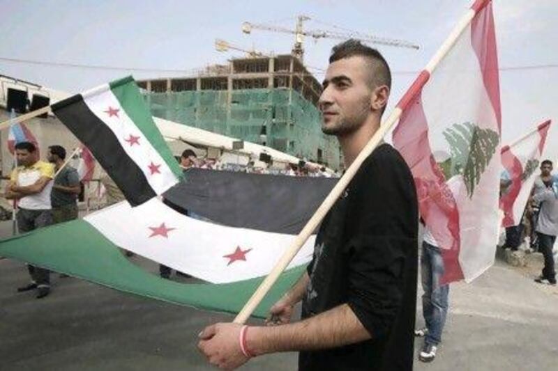 A man carries a corner of the Syrian revolutionary flag and a Lebanese national flag, as  people gather in Beirut’s Martyrs Square before the funeral for the country's intelligence chief, Brig. Gen Wissam Al Hassan.