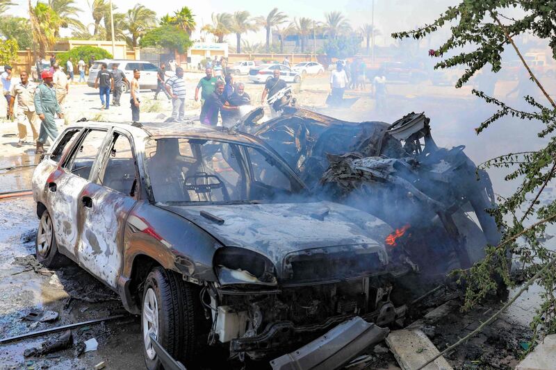 TOPSHOT - Libyans gather at the site of a car bomb attack in Libya's eastern city of Benghazi on August 10, 2019. "Two members of the UN mission, one them a foreigner, were killed and at least eight others wounded including a child, by a car bomb" in a shopping area of the Al-Hawari district, the official said. / AFP / -

