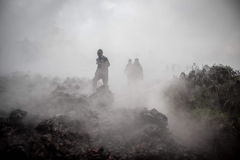 Men cross the front of the still smoking lava rocks from an eruption of the Mount Nyiragongo in Goma in the East of the Democratic Republic of Congo. AFP