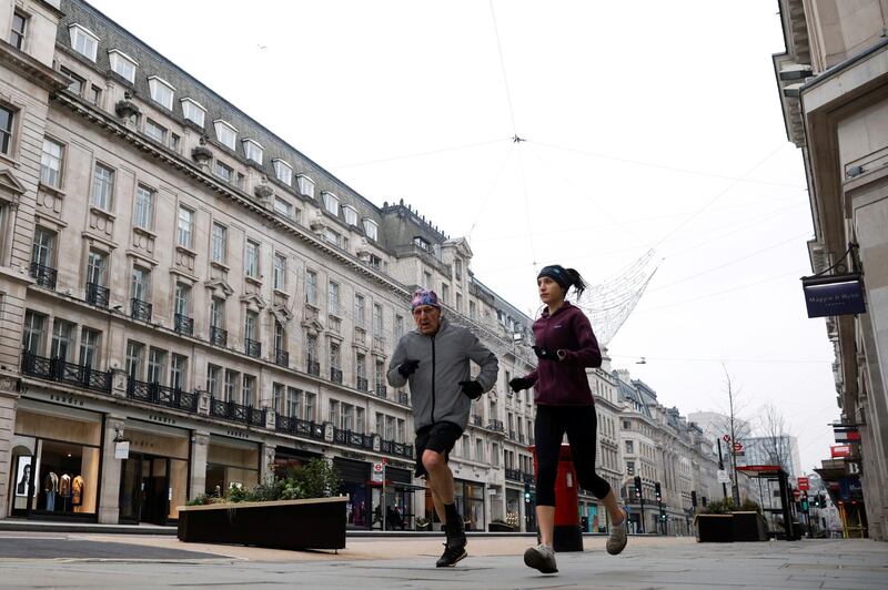 People jog down almost empty Regent Street in London. Reuters