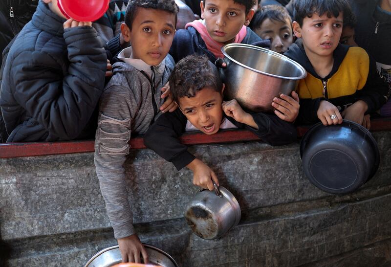 Palestinian children wait to receive food cooked by a charity kitchen amid a shortage of supplies in Rafah, the southern Gaza Strip. Reuters