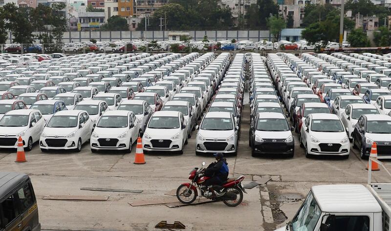 An Indian motorist rides past parked Hyundai vehicles ready for shipment at a port in Chennai on December 1, 2017. (Photo by ARUN SANKAR / AFP)