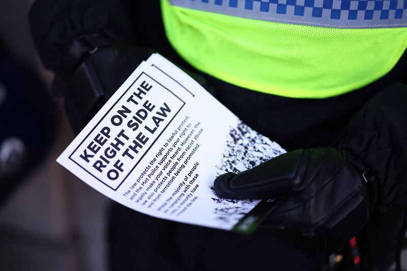 A police officer hands out leaflets reminding demonstrators to 'stay on the right side of the law'. AFP
