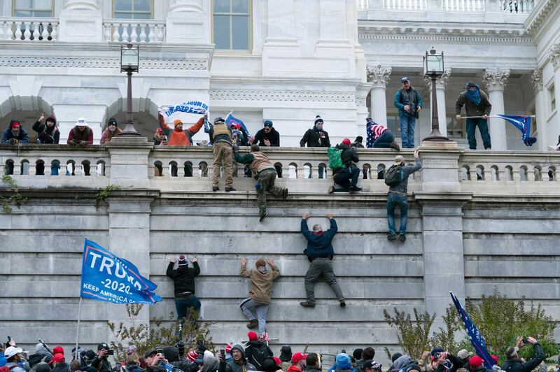 FILE - In this Jan. 6, 2021 file photo, violent insurrectionists loyal to President Donald Trump  scale the west wall of the the U.S. Capitol in Washington. Many of those who stormed the Capitol on Jan. 6 cited falsehoods about the election, and now some of them are hoping their gullibility helps them in court. Attorneys for several defendants facing charges connected to the deadly insurrection say they will raise their client's belief in conspiracy theories and misinformation, either as an explanation for why they did what they did, or as an attempt to create a little sympathy. (AP Photo/Jose Luis Magana, File)