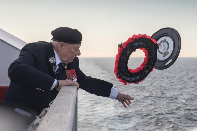 John Quinn, a Royal Marine who was a coxswain on a landing craft at Gold Beach throws a wreath into the sea.