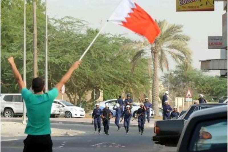 A protester waves the Bahraini flag as anti-riot police storm Duraz village, north of Manama, yesterday. Most of Bahrain's Shiite villages and parts of Manama saw marches just hours after martial laws was lifted. Mazen Mahdi / EPA