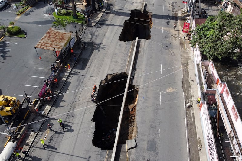 Aerial view of two giant holes in a road, caused by the collapse of a drainage system due to heavy rains that hit the country, in Villa Nueva, 15 km south of Guatemala City, on September 25, 2022.  - Four people traveling in a car suffered injuries and were taken to a hospital after they fell into a giant hole in a road, rescuers said.  (Photo by Johan ORDONEZ  /  AFP)