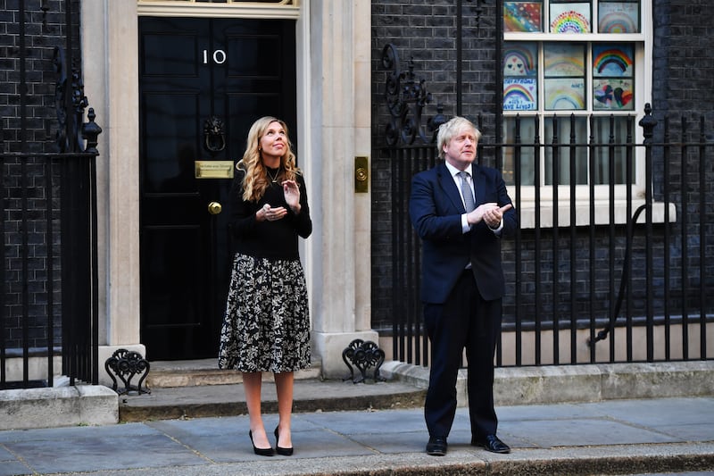 Mr Johnson and his fiancee Carrie Symonds applaud key workers outside 10 Downing Street in May 2020, during the coronavirus pandemic. Getty Images