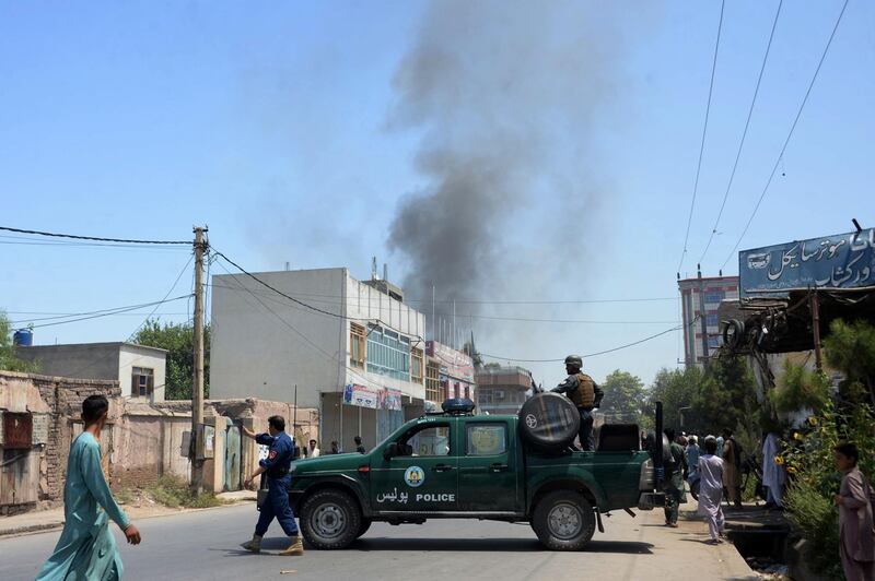 Afghan security personnel secure a road as smoke billows from the site of suicide attack as an ongoing attack between Afghan security force and suicide attackers in Jalalabad on July 31, 2018. 
Gunmen stormed a government building after multiple explosions in an ongoing attack in the eastern Afghan city of Jalalabad on July 31, an official said. At least two explosions were heard before the attackers entered the refugees and repatriation department compound, provincial governor spokesman Attaullah Khogyani said. Several international organisations are also in the vicinity.
 / AFP PHOTO / NOORULLAH SHIRZADA