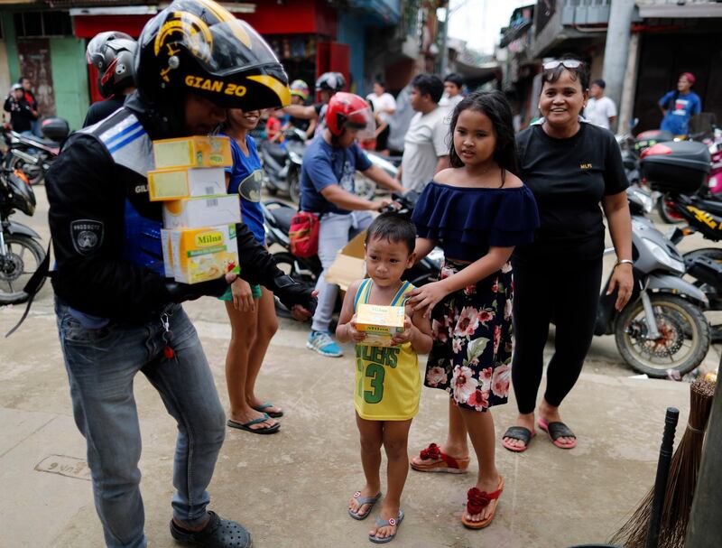 Filipino villagers receive boxes of goods from a motorcycle rider.  EPA