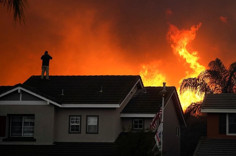 Herman Termeer, 54, stands on the roof of his home as the Blue Ridge Fire burns along the hillside in Chino Hills, California. AP Photo