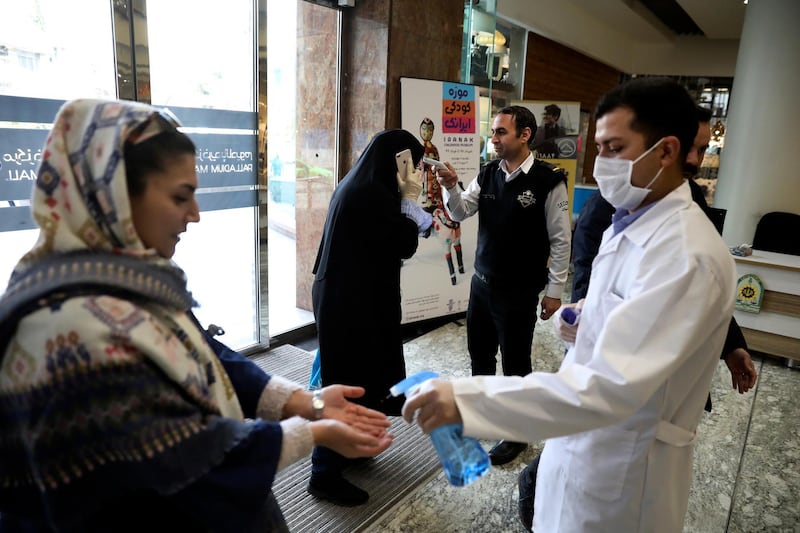 People have their temperature checked and their hands disinfected as they enter the Palladium Shopping Centre, in northern Tehran, Iran. AP Photo