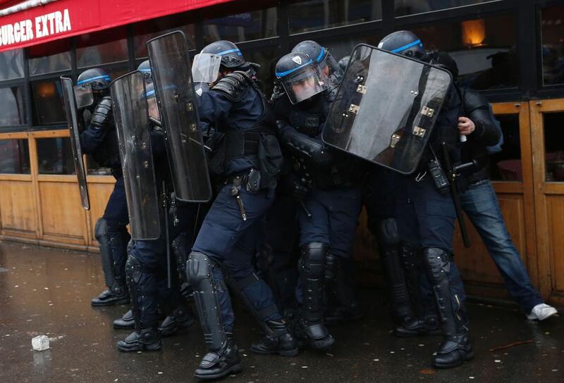 French riot police take cover during a protest by unions and students in Paris. Thomas Samson / AFP Photo