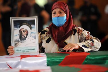 An Algerian woman holds a drawing of a fights as she mourns over one of the national flag-draped coffins containing the remains of 24 Algerian resistance fighters decapitated during the French occupation of the country, at the Moufdi-Zakaria culture palace in Algiers, Algeria, 4 July, 2020. EPA