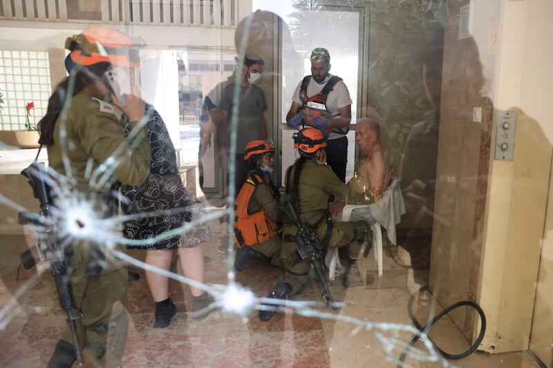 Israeli rescuers tend to an elderly man at the entrance of a building in Ashkelon struck by a rocket fired from the Gaza Strip. AFP
