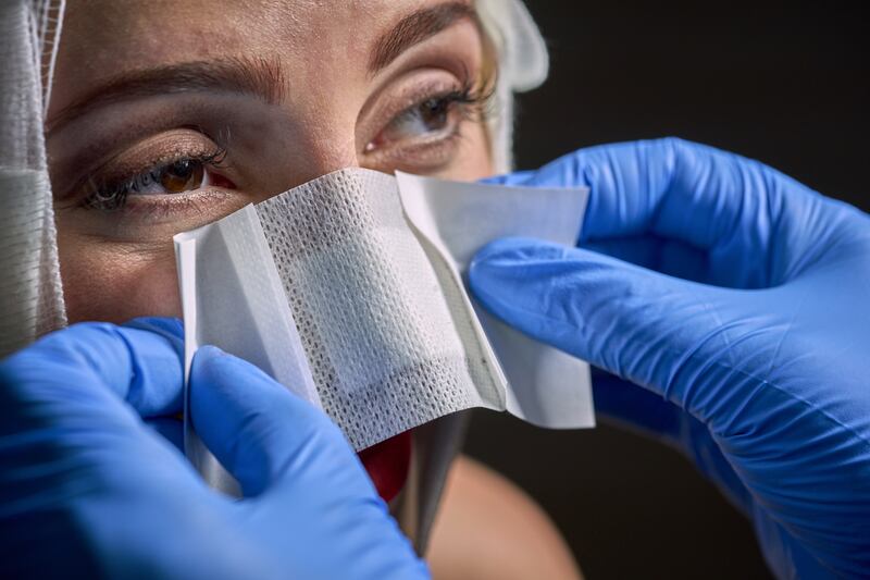 A woman has a bandage applied to her nose. Getty Images