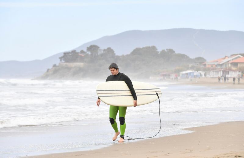 A surfer walks on the beach in Castiglione della Pescaia, Italy. Reuters