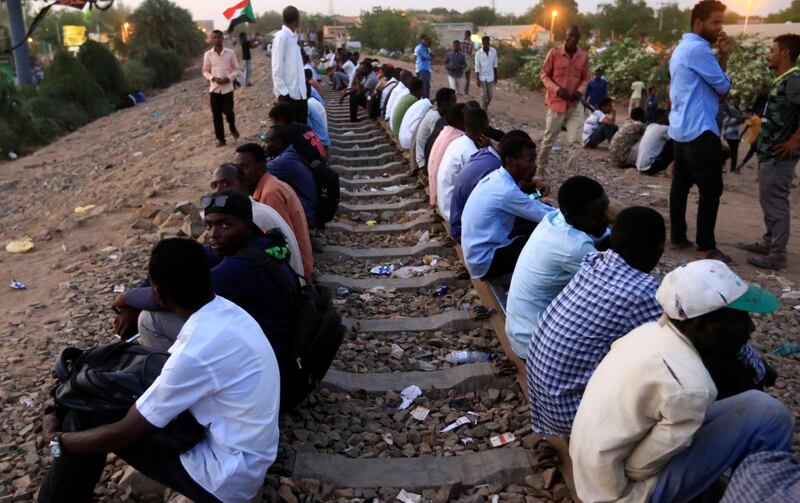 Sudanese demonstrators sit on the railway to block the train from passing through, during a protest outside the Defence Ministry in Khartoum. Reuters