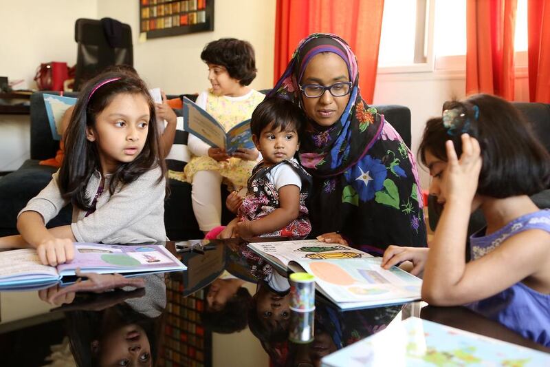 Sadia Anwar, centre, founder of the Dubai group Bismillah Babies, helps children to read the book, My Ramadan Journal – Around the World. Pawan Singh / The National 