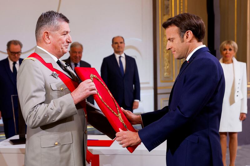 Emmanuel Macron is presented with the necklace of the Grand Master of the Legion of Honour, France's highest distinction, by Gen Benoit Puga at the Elysee presidential palace in Paris. Mr Macron was sworn-in for a second term as France's president on Saturday. AP