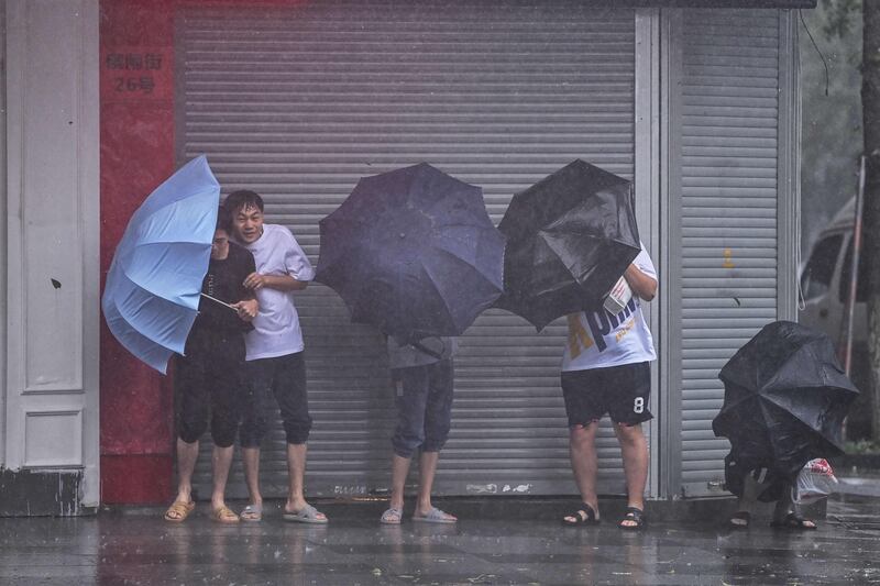 Pedestrians seek shelter from the rain and wind in Ningbo, Zhejiang province, as Typhoon In-Fa approaches China's east coast. AFP