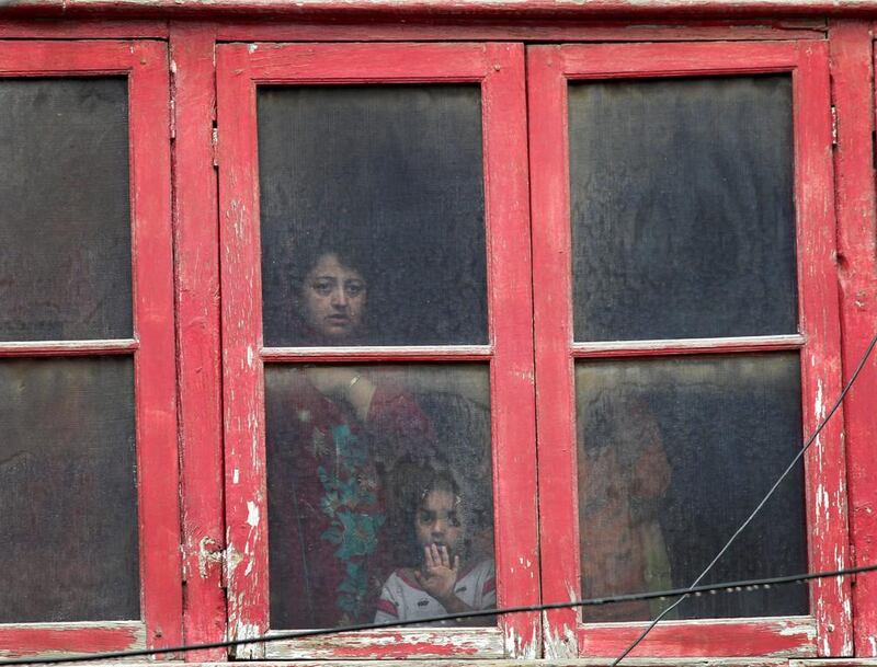 A Kashmiri family look out from the window of their house near the site of a gunbattle in Srinagar.  Mukhtar Khan / AP Photo