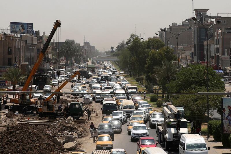 Iraqi drivers steer their cars in traffic jams next to street works in Baghdad. AFP
