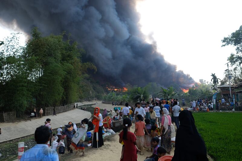 Rohingya refugees try to salvage their belongings after as the fire rages. AP