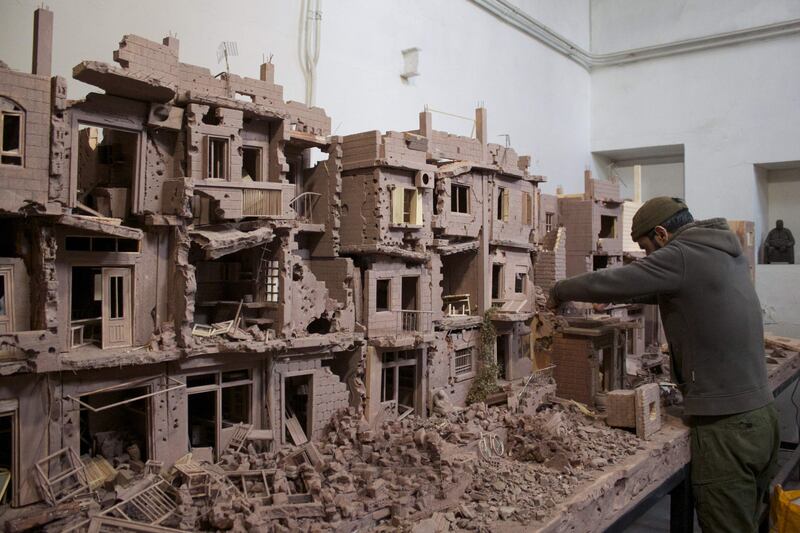 Syrian sculptor Khaled Dawwa works on a clay sculpture depicting a street in Syria, destroyed by Syrian regime forces and their allies, in Vanves, on the outskirts of Paris  on January 9, 2022.  (Photo by Lucie PEYTERMANN  /  AFP)