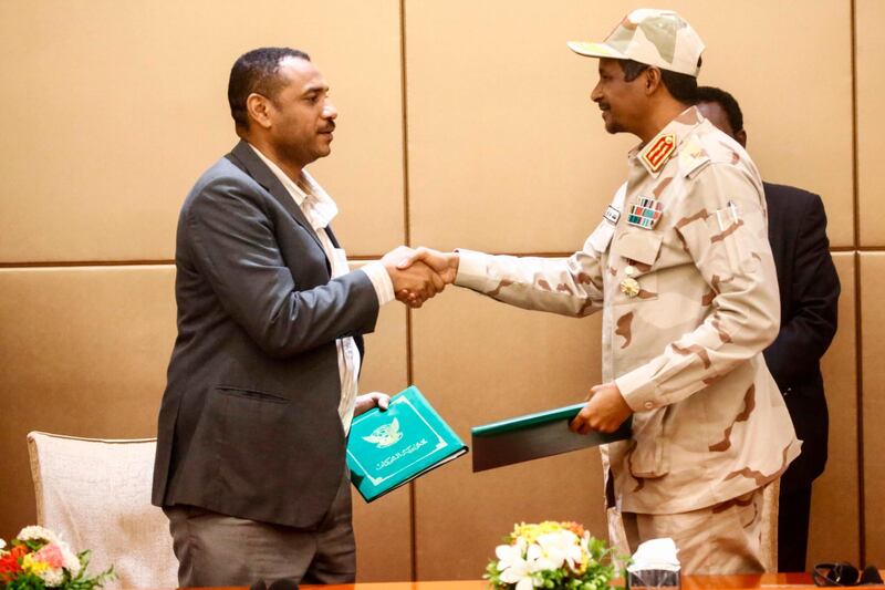 General Mohamed Hamdan Daglo (R), Sudan's deputy head of the Transitional Military Council, and Protest leader Ahmed Rabie shake hands after signing the constitutional declaration at a ceremony attended by African Union and Ethiopian mediators in the capital Khartoum on August 4, 2019. Sudan's army rulers and protest leaders today inked a hard-won constitutional declaration, paving the way for a promised transition to civilian rule. The agreement, signed during a ceremony witnessed by AFP,  builds on a landmark power-sharing deal signed on July 17 and provides for a joint civilian-military ruling body to oversee the formation of a transitional civilian government and parliament to govern for a three-year transition period. 
 / AFP / ASHRAF SHAZLY
