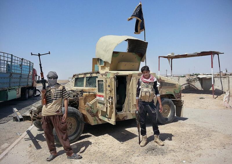 In this file photo taken on June 19, 2014, ISIL militants stand with a captured Iraqi army Humvee at a checkpoint outside Beiji refinery, some 250 kilometers north of Baghdad, Iraq. In mid-November, Shiite general Abdul-Wahab Al Saadi's forces successfully recaptured the oil refinery city of Beiji from the militants. AP Photo