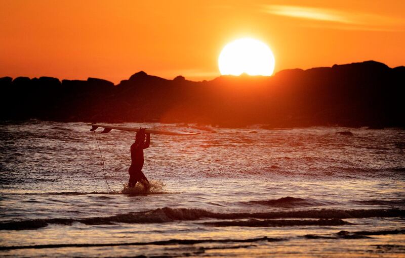 A surfer at Tynemouth beach in North Tyneside, UK, braves the low temperatures. PA via AP