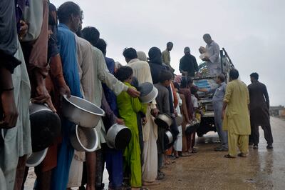 People wait their turn to get free food distributed by volunteers outside a camp for those displaced from coastal areas due to Cyclone Biparjoy, in Sujawal, in Sindh province. AP
