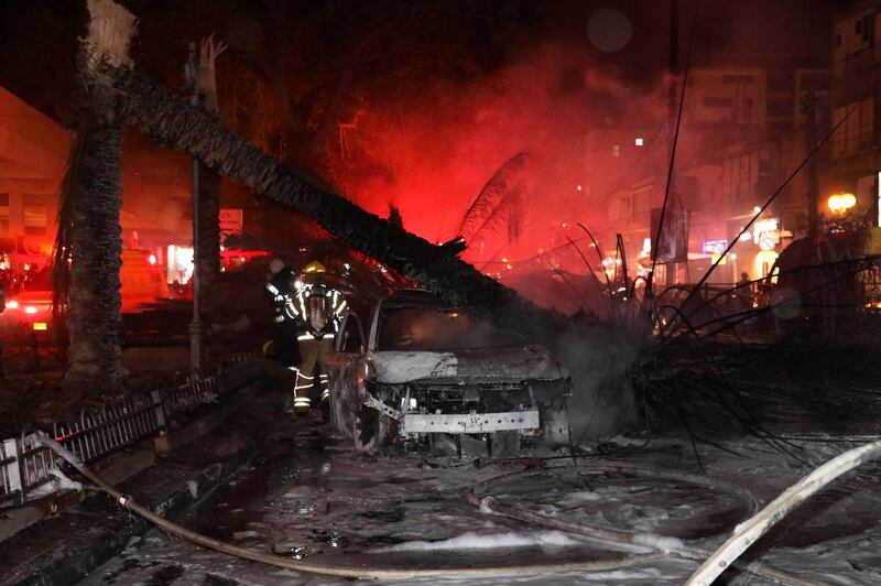 Israeli firefighters walk by a car with a fallen tree on it after it was hit by a rocket fired from Gaza towards Holon, Israel. Reuters