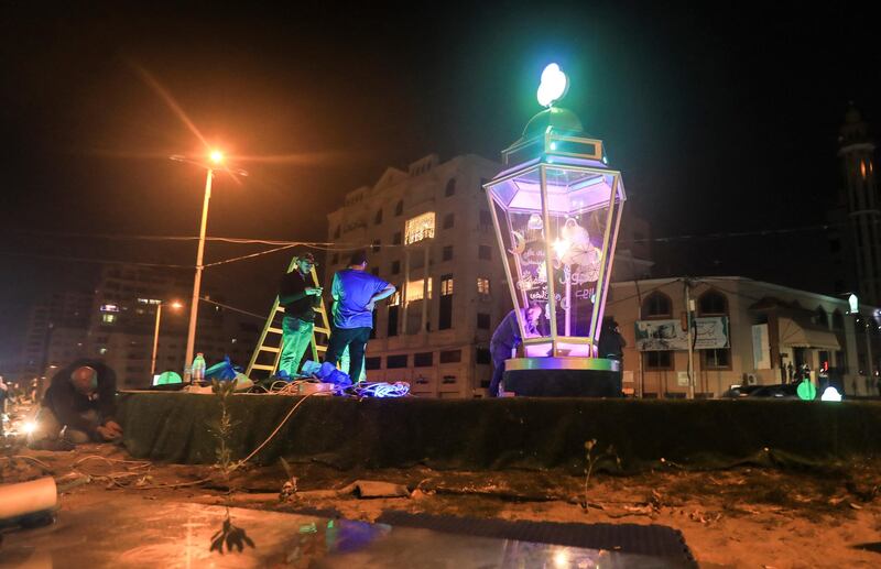 Workers install a giant traditional "fanous" lantern, a decoration used to celebrate the start of the Muslim holy month of Ramadan, at al-Shati camp for Palestinian refugees in the central Gaza Strip on April 23, 2020. - From cancelled iftar (fast breaking) feasts to suspended mosque prayers, Muslims across the Middle East are bracing for a bleak month of Ramadan fasting as the threat of the COVID-19 pandemic lingers. The holy Muslims fasting month of Ramadan is a period for both self-reflection and socialising. Believers fast from dawn to dusk and then gather around a family or community meal each evening of Islam's holiest month. (Photo by MAHMUD HAMS / AFP)