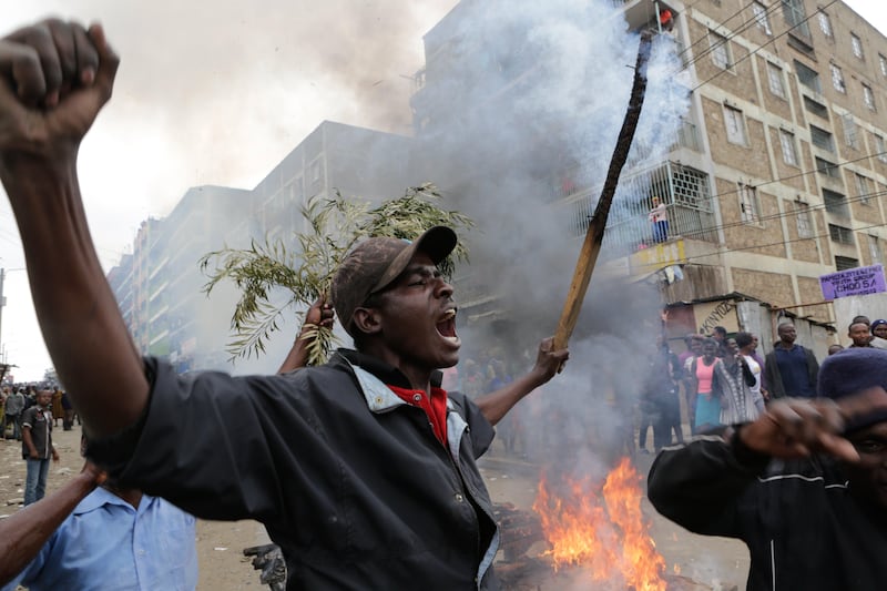 A supporter, left, of the opposition leader Raila Odinga who leads The National Super Alliance (NASA) coalition, holds a burning stick next to a burning barricade during a protest after Odinga announced that he rejects the provisional result of the presidential election announced by the electoral body, in Mathare slums one of Odinga's strongholds in Nairobi. DANIEL IRUNGU / EPA