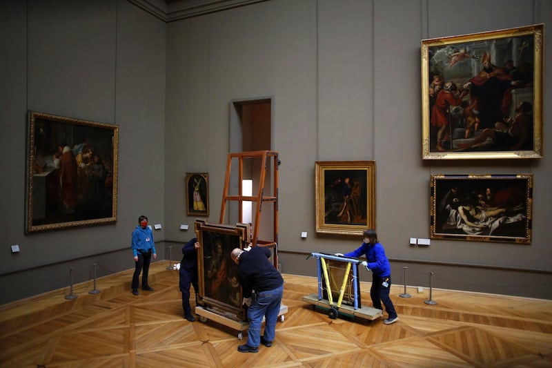 Workers at the Louvre in Paris handle a painting called 'Saint Louis, King of France, and his Page' by Spanish painter El Greco, as it returns from an exhibition at the Chicago Institute on February 9, 2021. AP