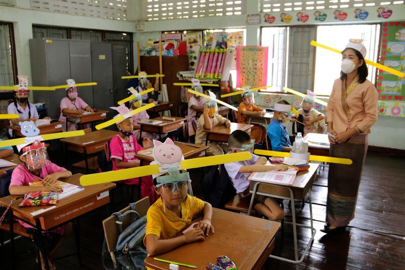 A teacher and students wear hats designed to maintain social distancing at Ban Pa Muad School in Chiang Mai, northern Thailand. AP Photo