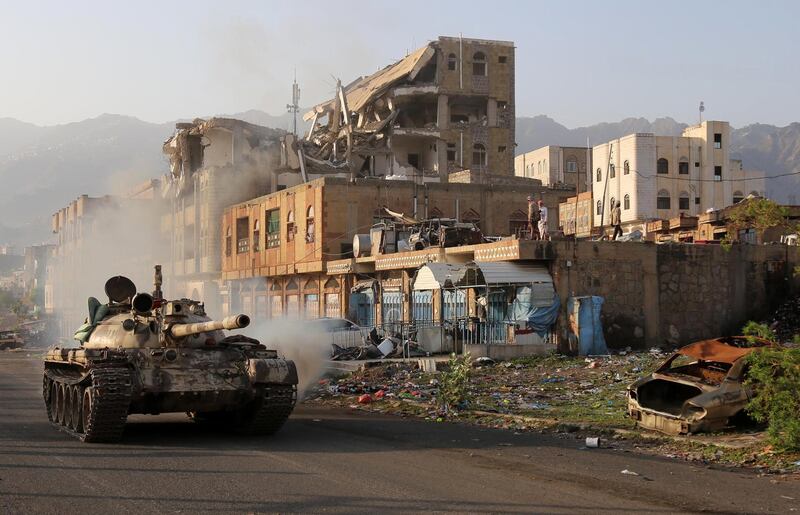 Yemeni fighters loyal to the country's exiled President Abedrabbo Mansour Hadi ride a tank past a destroyed building during clashes with Shiite Huthi rebels in the country's third-city of Taez on May 30, 2019. Taez, in southern Yemen, is under siege by the Huthis but controlled by pro-government forces, who are supported by the military coalition led by Saudi Arabia and the United Arab Emirates. / AFP / Ahmad AL-BASHA
