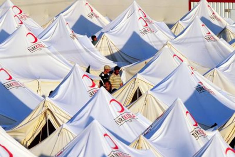 Syrian refugees walk betwen tents in the Boynuyogun Turkish Red Crescent refugee camp in the Altinozu district of Hatay, near the Syrian border, on June 20, 2011. Syrian opposition activists have set up a "National Council" to spearhead the battle to oust President Bashar al-Assad's regime, a group of dissidents, including their spokesman Jamil Saib, announced the day before. "We announce the creation of a National Council to lead the Syrian revolution, comprising all communities and representatives of national political forces inside and outside Syria," they told reporters a near the Turkish-Syrian border.
AFP PHOTO / MUSTAFA OZER
 *** Local Caption ***  257403-01-08.jpg