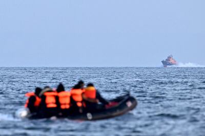 A Royal National Lifeboat Institution vessel approaches migrants in an inflatable boat crossing the English Channel, bound for Dover on the south coast of England.  AFP