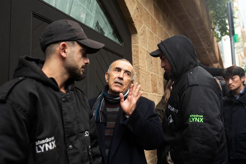 Private security guards flank a man, who identified himself as a family doctor, as he speaks to journalists as he enters the home of former Nissan Chairman Carlos Ghosn in Beirut. AP