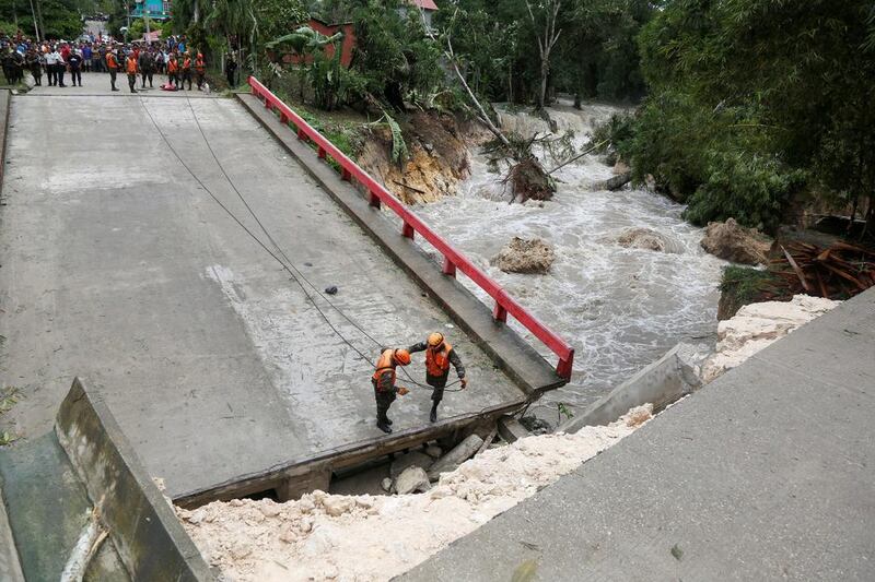 Members of Guatemalan emergency commission guard a bridge that collapsed after heavy rains in Menchor de Mencos, Guatemala. Luis Echeverria / Reuters