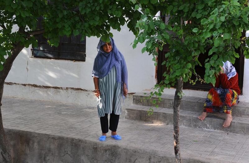 A female patient looks on as she stands next to an entrance outside of her ward.
