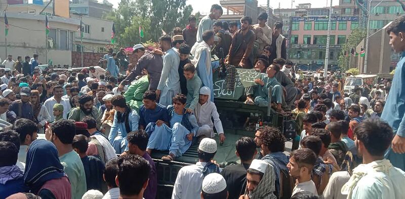 Taliban fighters and local people sit on an Afghan National Army armoured vehicle on a street in Jalalabad province on August 15, 2021. AFP