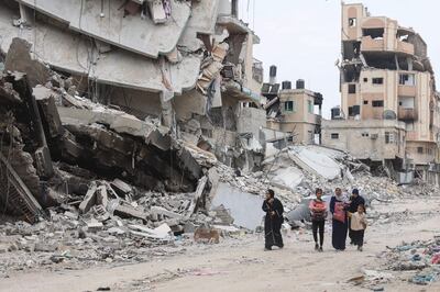 Palestinian women and children walk past the ruins of buildings destroyed by earlier Israeli bombardment in Gaza City. AFP