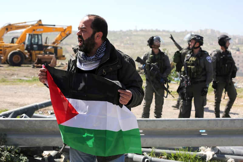A Palestinian man takes part in a demonstration in the West Bank town of Abu Dis on March 6, 2015 against Palestinian land confiscation, as Israeli secrity forces stand guard. Abbas Momani/AFP Photo

