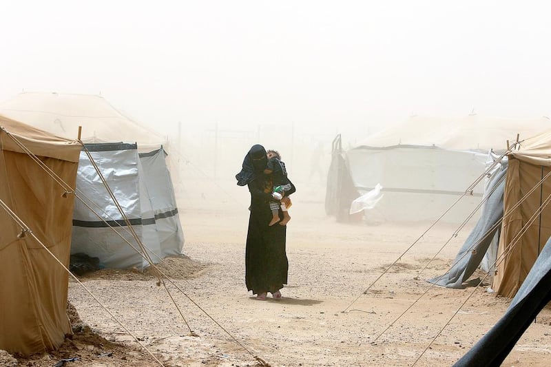 A woman, who fled from Fallujah because of ISIL violence, carrying her child during a dust storm at a refugee camp in Ameriyat Falluja, south of Fallujah, Iraq, June 16, 2016. Ahmed Saad/Reuters