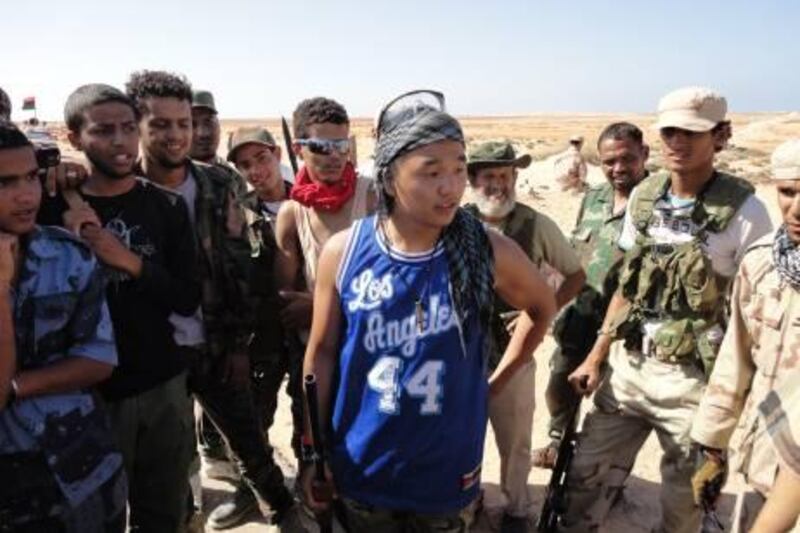 Caption: August 30, An Nawfiliyah, Libya. Chris Jeon, 21, decided to travel to Libya to join the rebels for the last month and a half of his summer vacation. He is entering his senior year at University of California - Los Angeles, where he is studying math. Here he is surrounded by fellow rebels who are amassing about 130 km from Col Muammar Qaddafi's hometown and stronghold.         Photo: Bradley Hope/The National